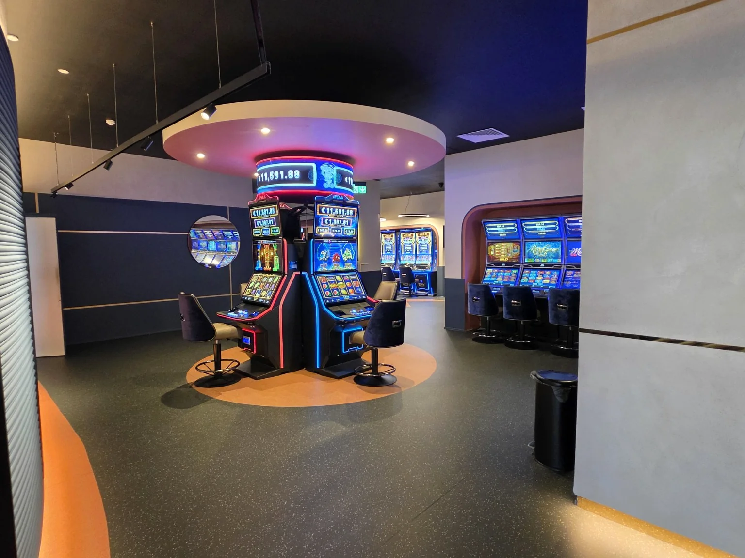 Central bank of gaming machines beneath modern circular ceiling feature