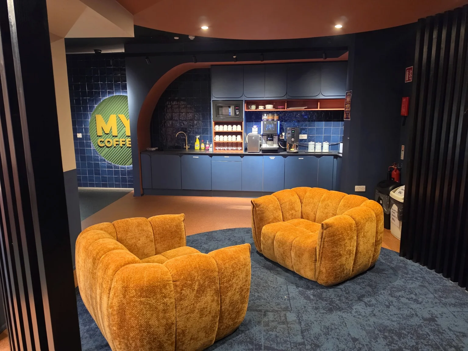 Modern coffee area with warm orange lounge chairs